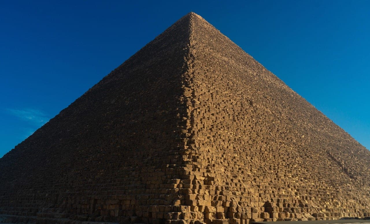 The edge of a great pyramid at Giza against a deep blue sky.