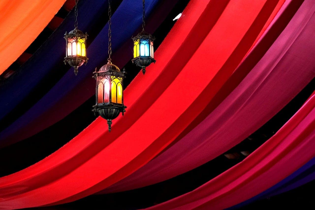 Three coloured-glass lanterns hanging beneath a red and purple fabric canopy.