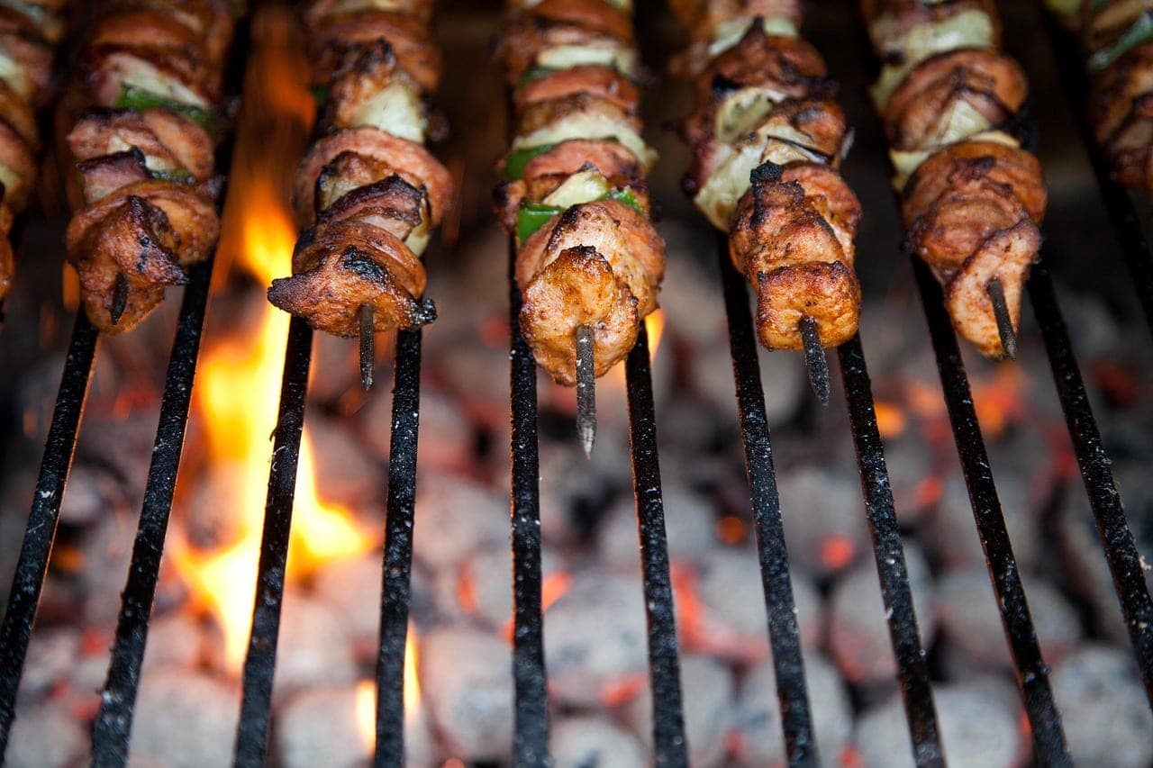 Golden meat skewers on the grate, over a charcoal fire.