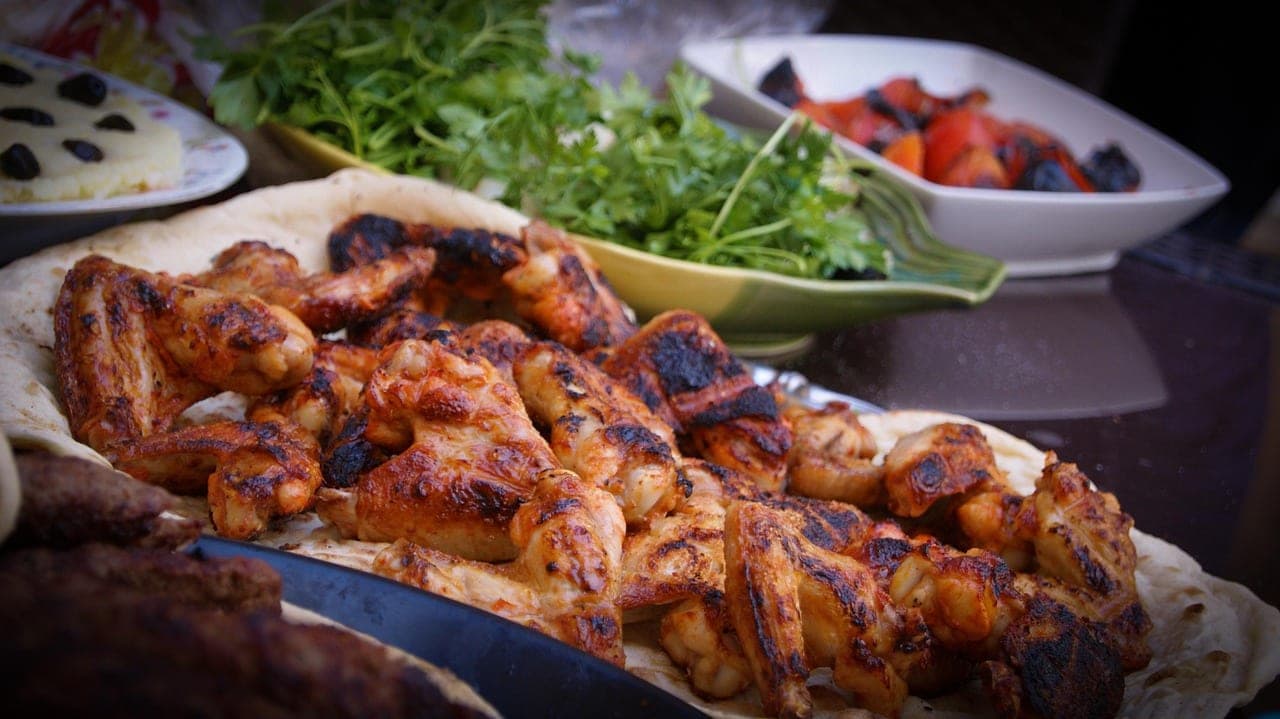 Grilled chicken pieces on flatbread, with parsley and grilled tomatoes.