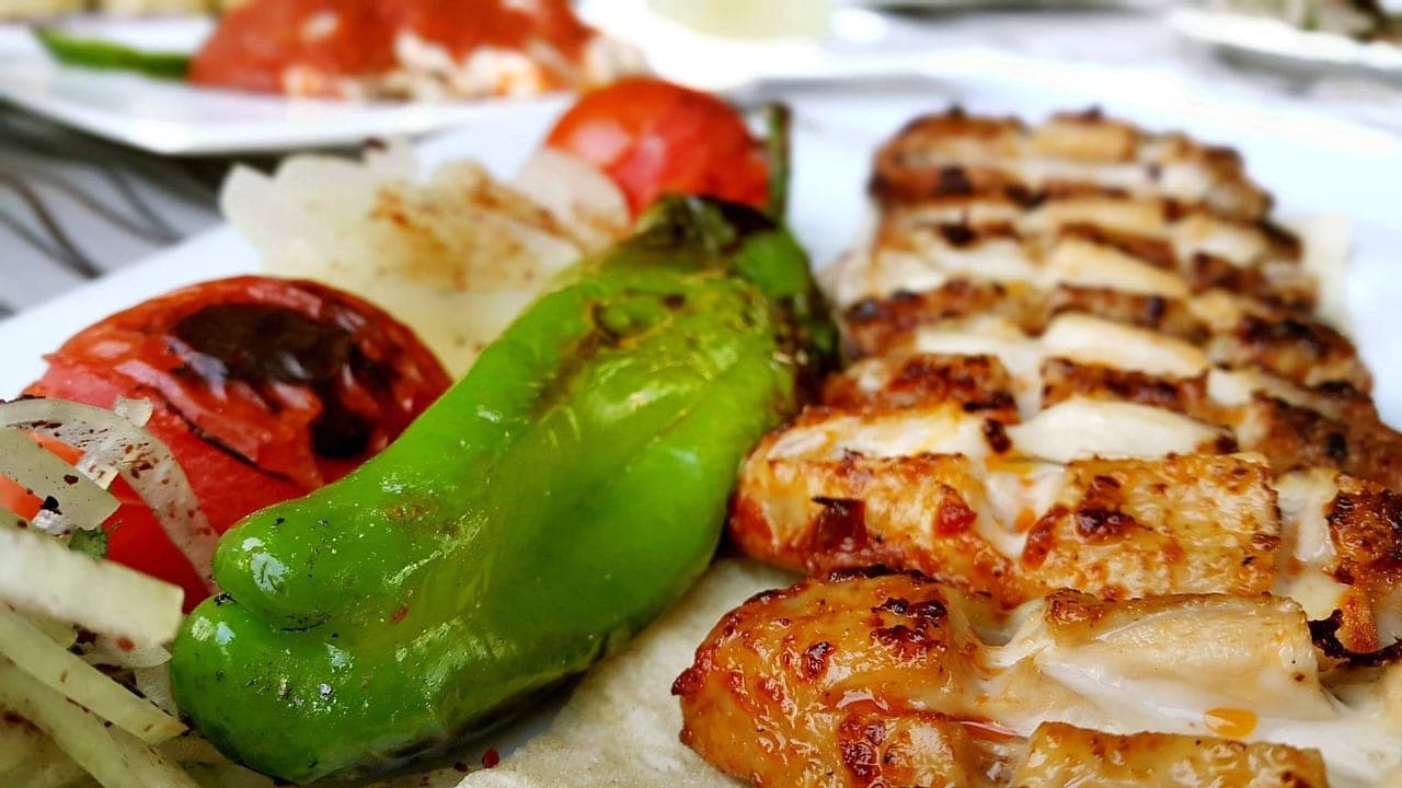 Pieces of grilled chicken laid on flatbread, with a fire-roasted green pepper and tomato.