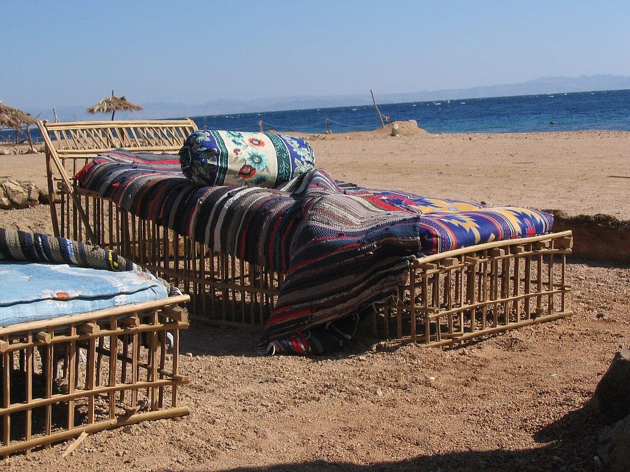 Bamboo benches spread with striped mattresses and cushions, set right on the sand facing the sea.