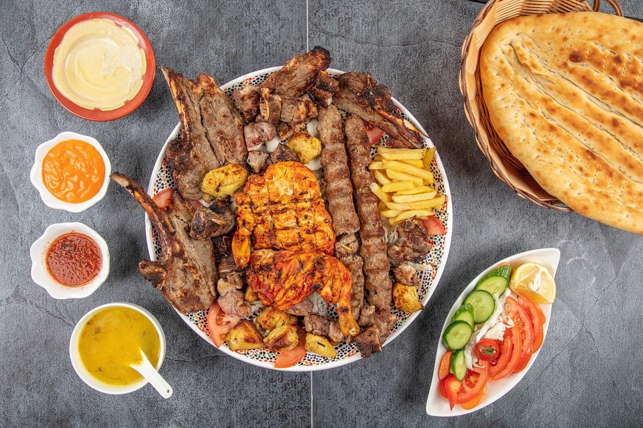 A large mixed grill platter — skewers, chops and chicken — with bread, salad and sauces.