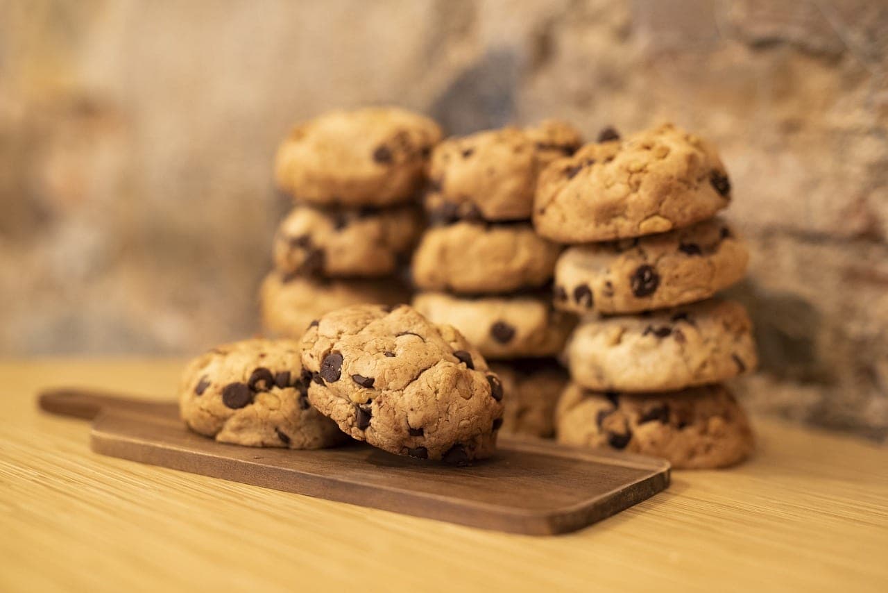 Chocolate-chip cookies stacked on a wooden board.