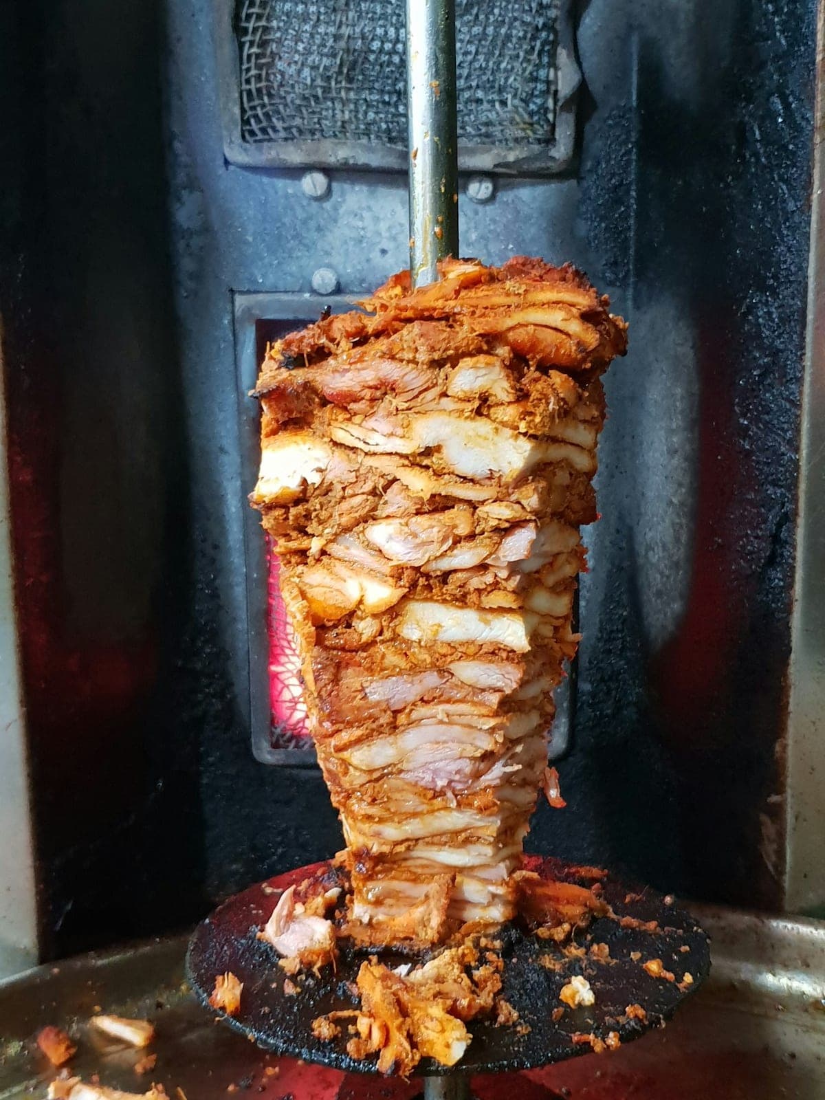 A shawarma spit turning in front of the grill