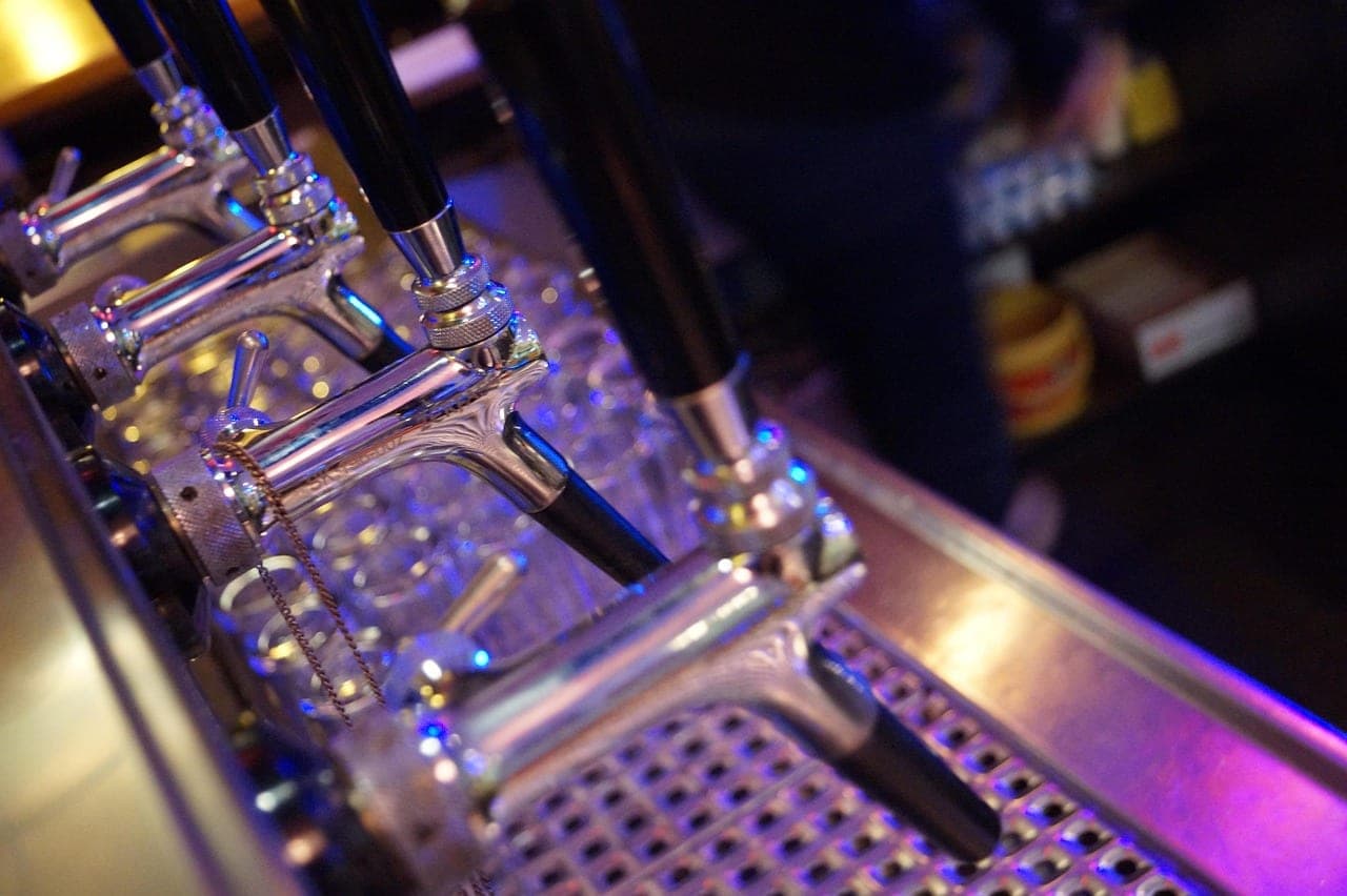 A row of chrome beer taps on a pub counter in the evening.