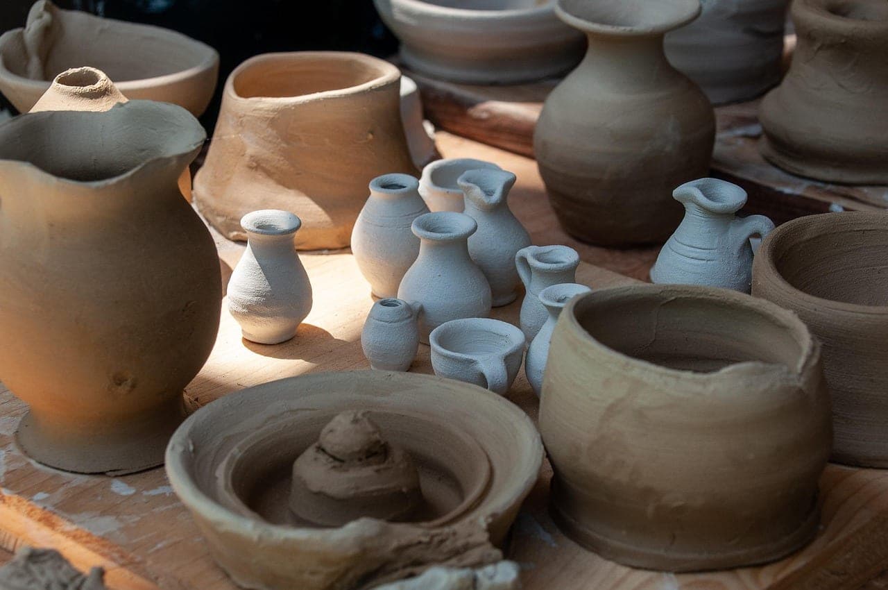 Unfired clay pots drying on a workshop bench.