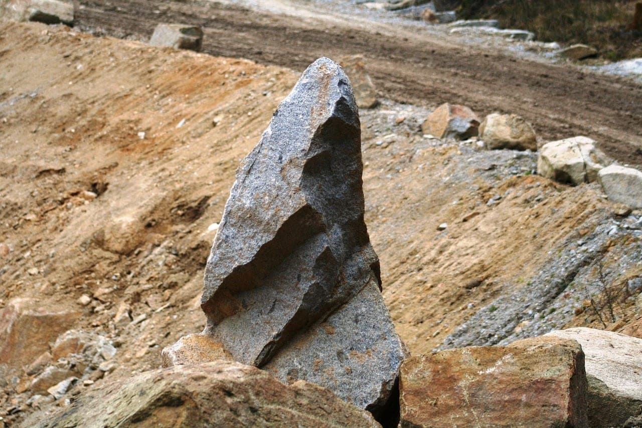 A split granite block standing in the middle of a stone quarry.