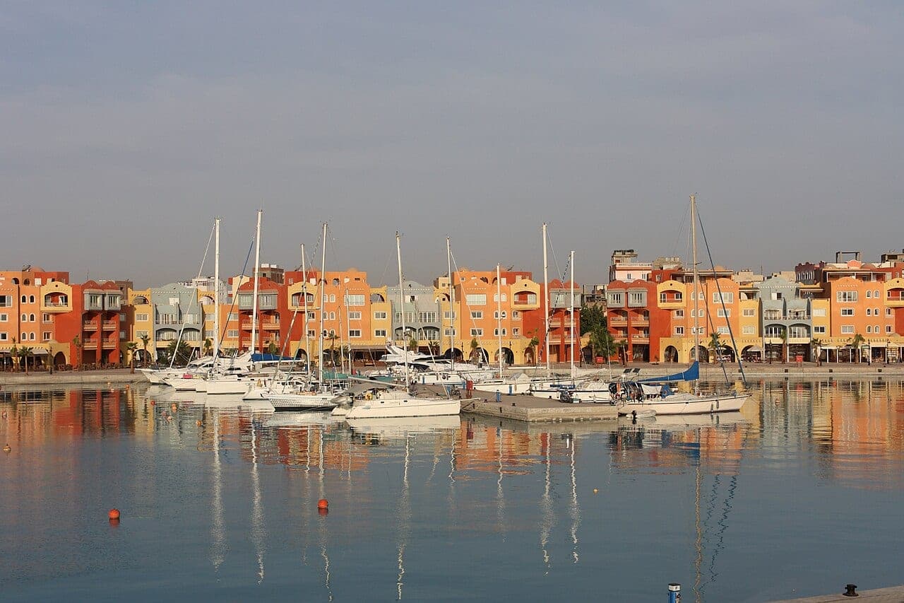 The ochre facades of Hurghada Marina and the sailboat masts, mirrored in the calm morning water.
