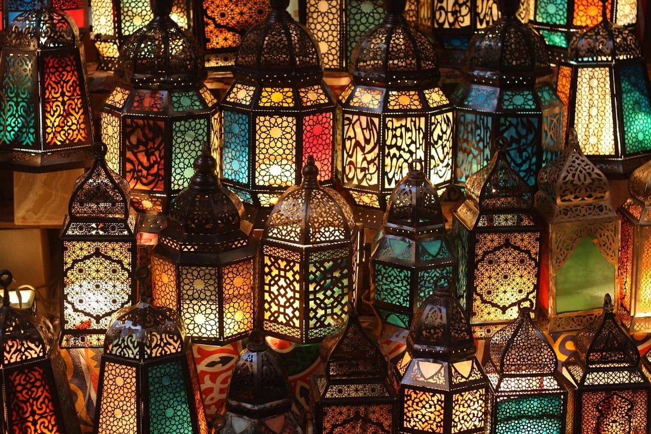 Pierced-metal lanterns with coloured glass, lit up.