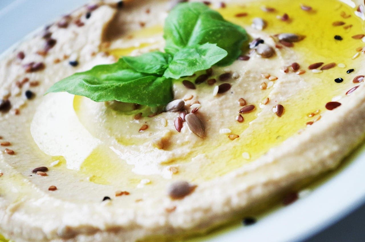 Smooth hummus, drizzled with olive oil and scattered with seeds.