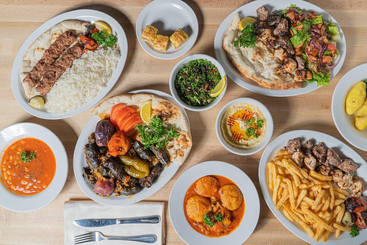 A table laid with stews, rice, hummus and flatbreads.