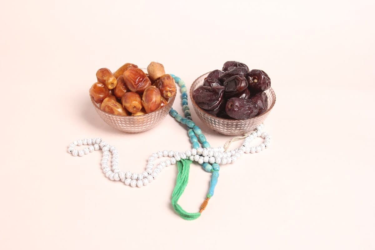Two bowls of dates and prayer beads, set side by side