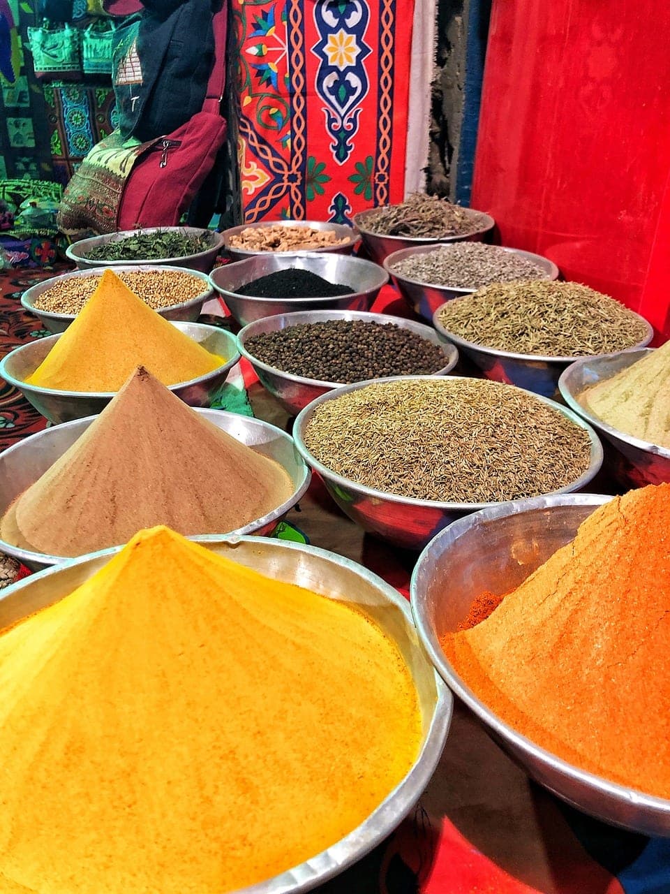 Cones of spices in large metal basins.