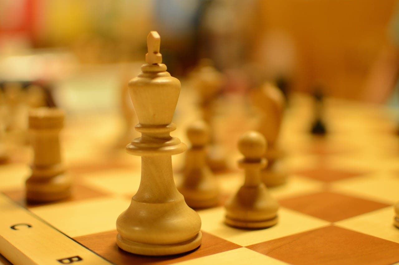 A wooden king and pawns on a chessboard, a game under way.