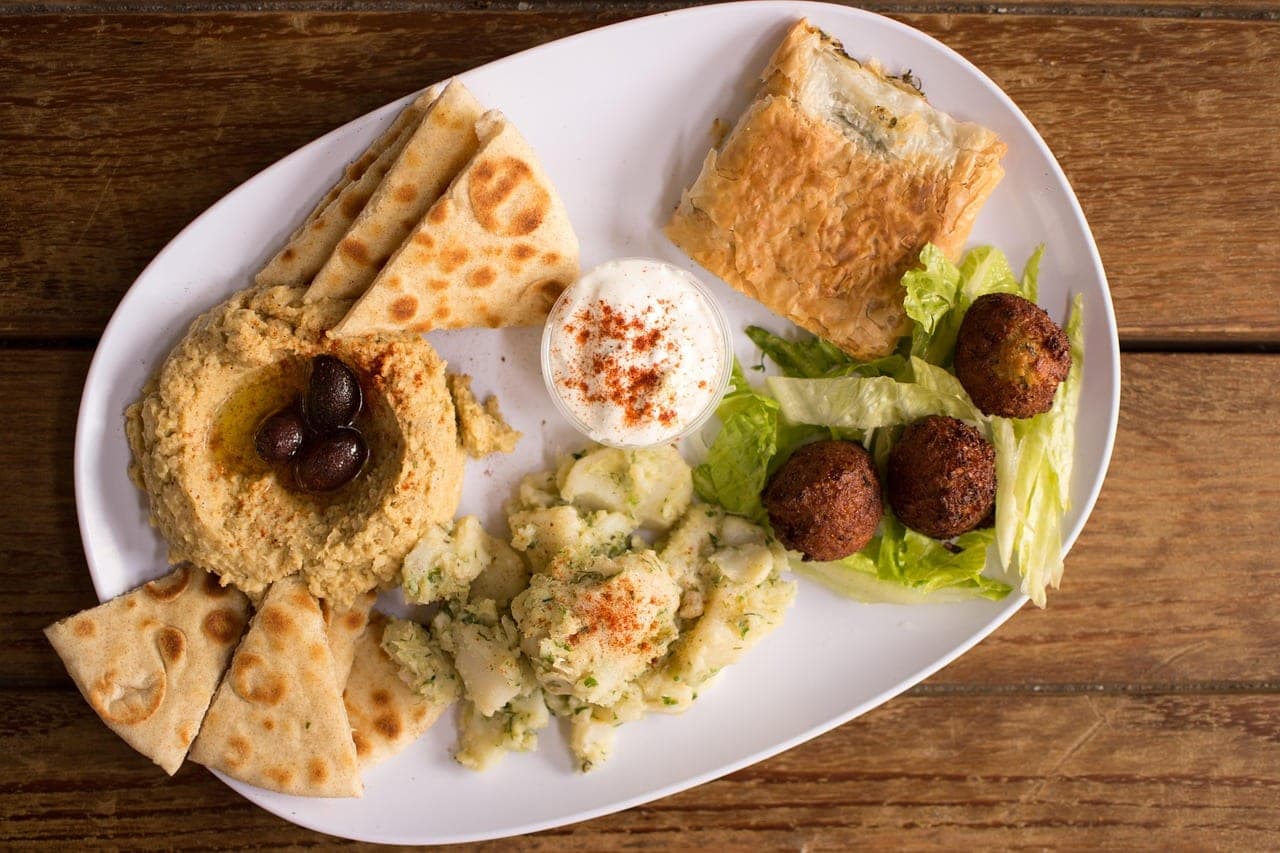 A mezze plate: hummus with olives, flatbread, falafel and salad.
