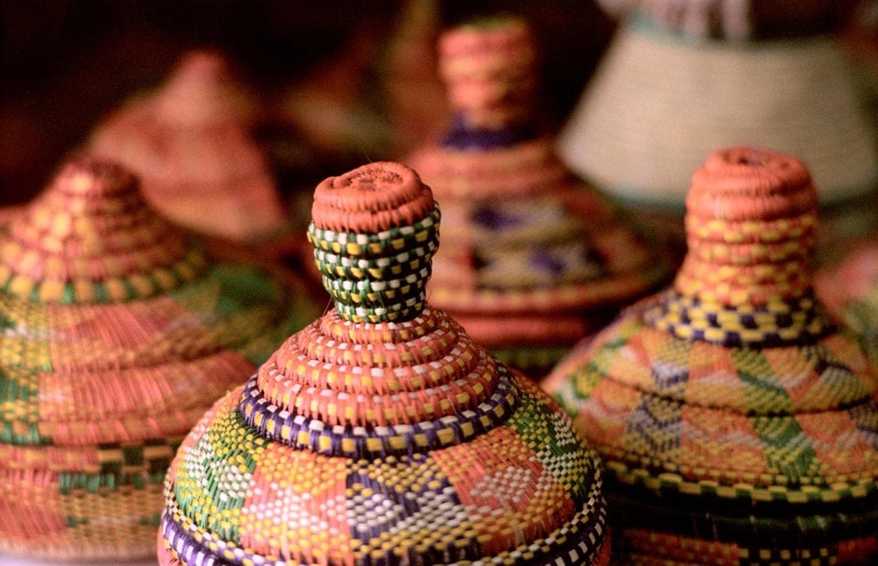 Coiled baskets with conical lids, in coloured geometric patterns.