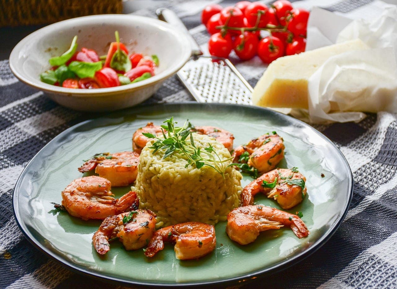 Sautéed prawns arranged around a mound of rice on a plate.