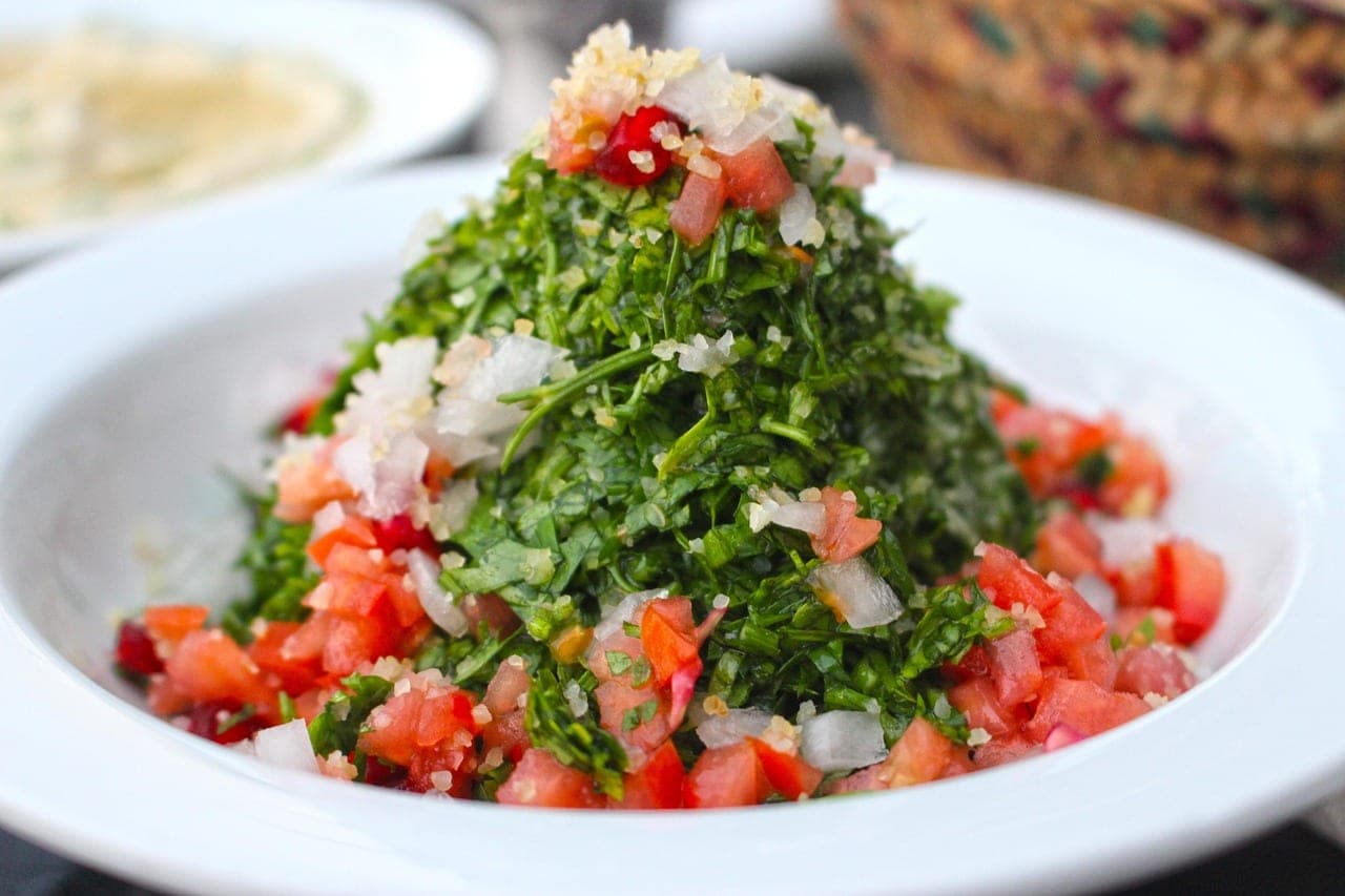 A mound of tabbouleh — parsley, tomato, onion and bulgur — on a white plate.