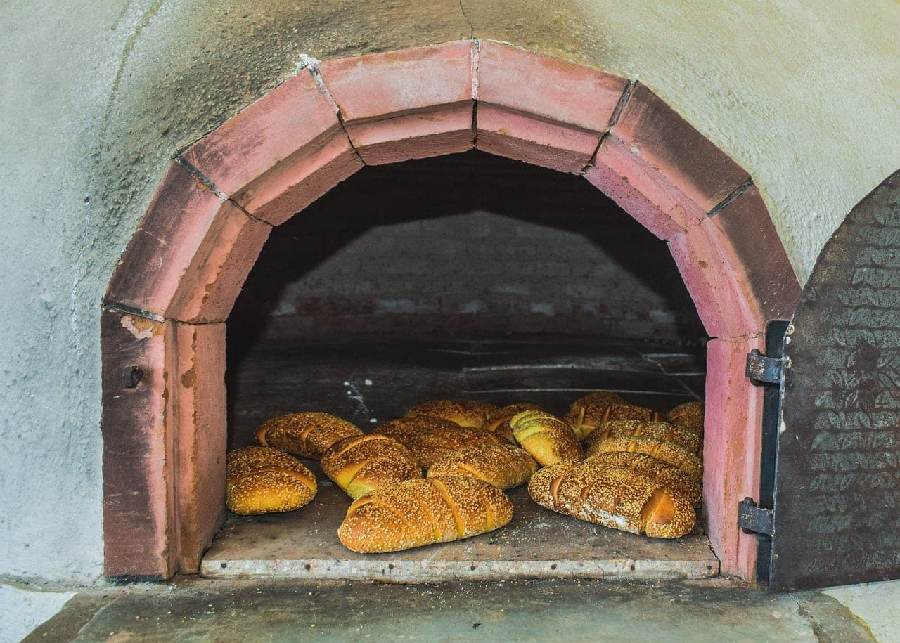 Sesame-crusted loaves baking on the stone floor of a masonry oven.