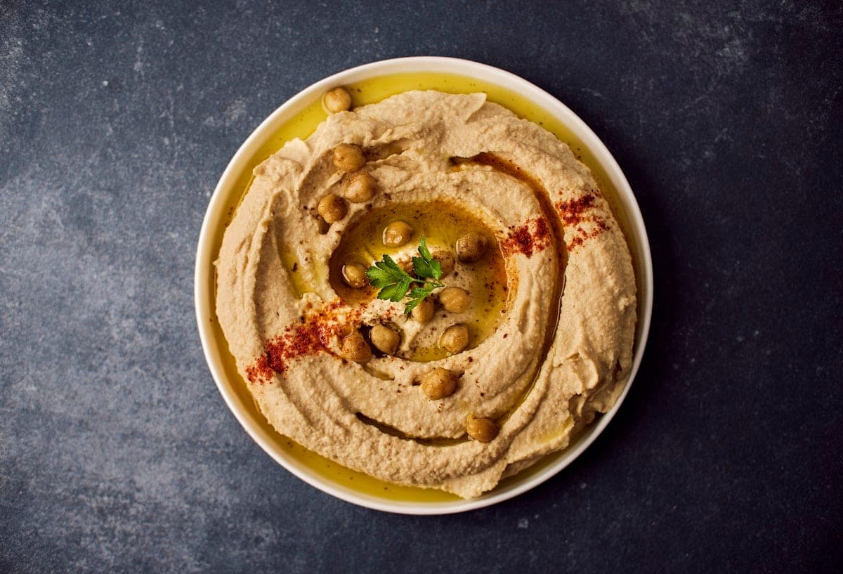 Smoothed hummus, a thread of oil and whole chickpeas