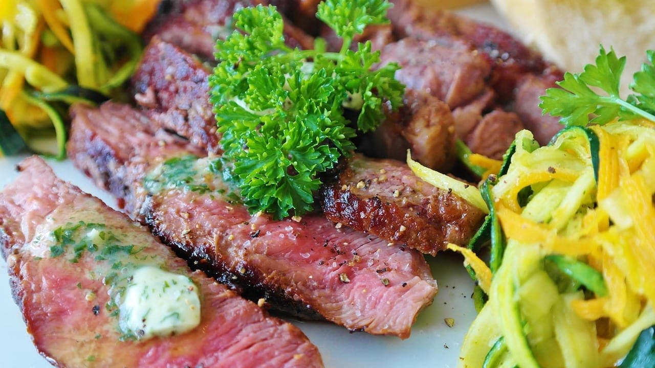 A grilled beef steak, sliced, with herb butter.