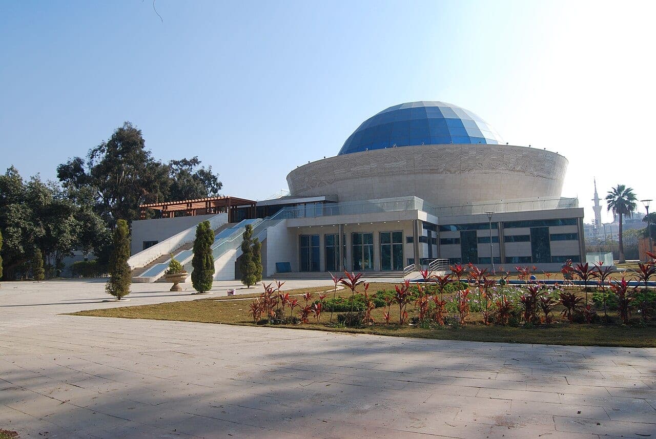 The centre's façade and its blue glass dome, the planetarium's, above a flower bed.