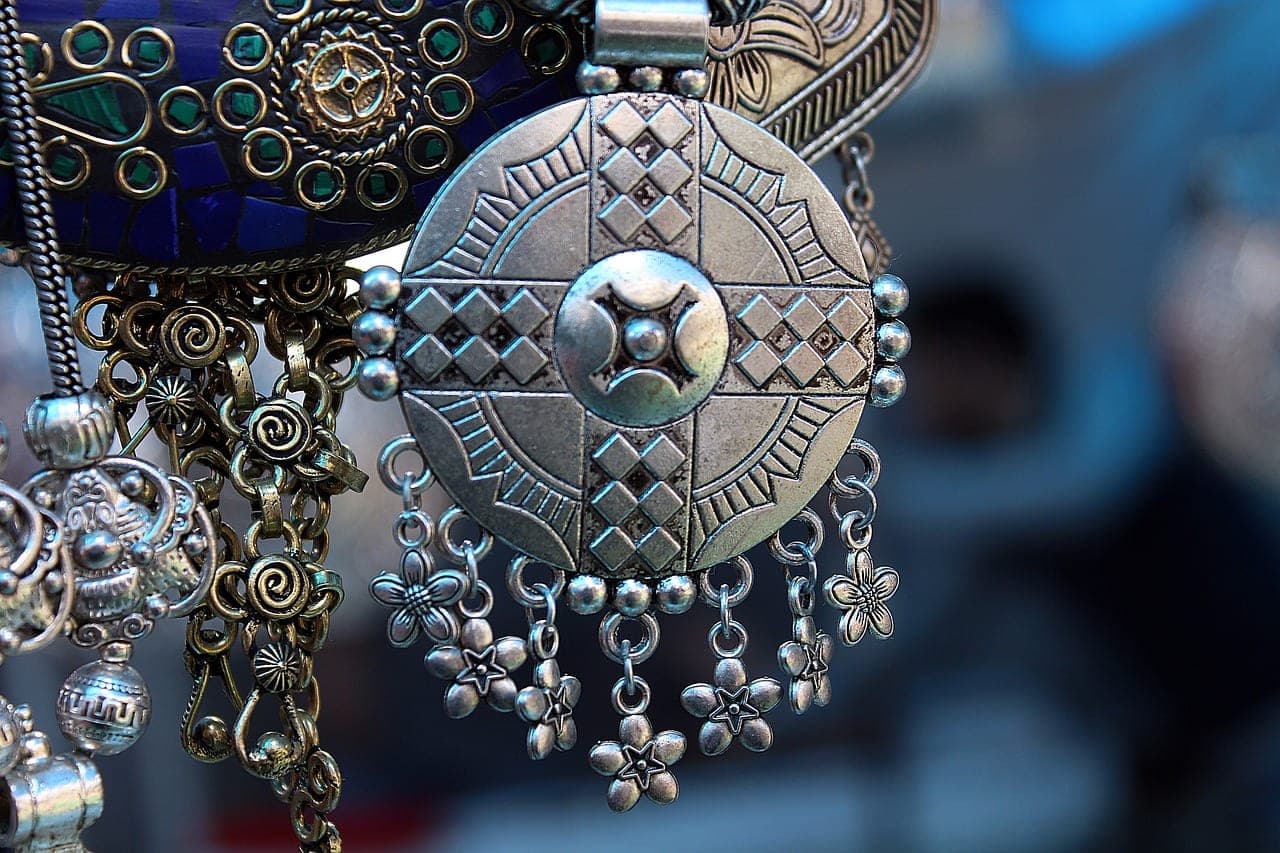 A large chased silver medallion hung with flower-shaped drops.
