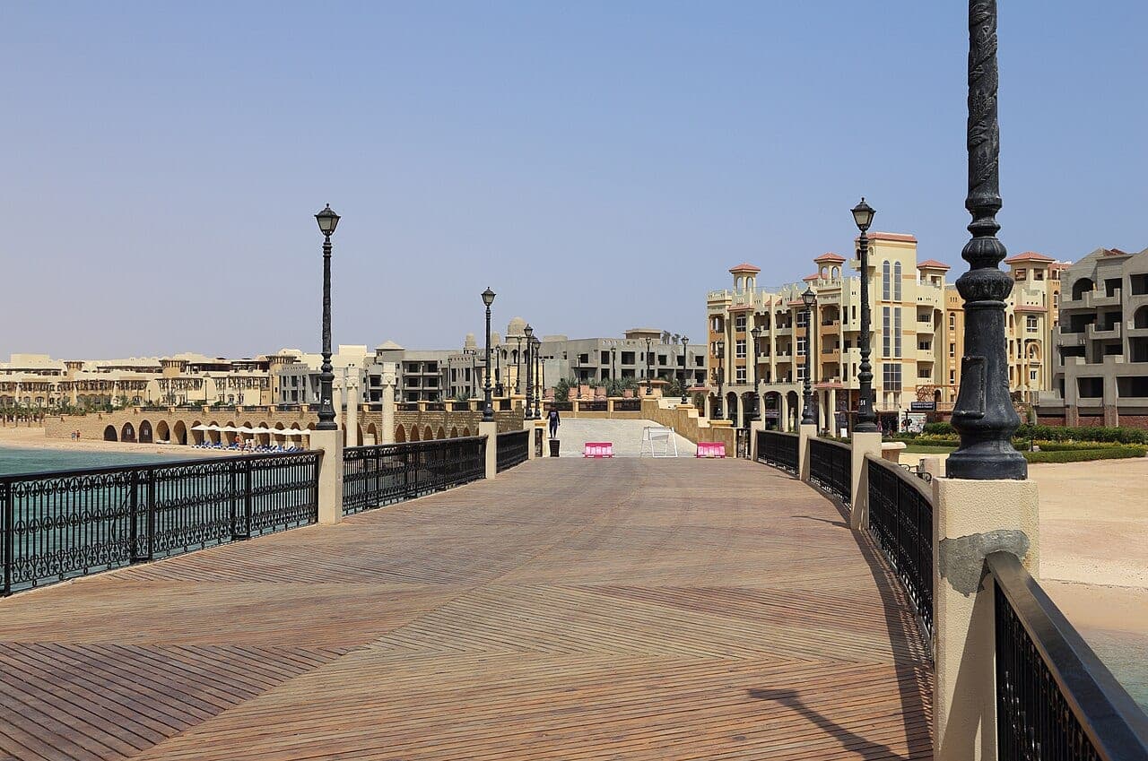 The promenade's wooden footbridge, its lamp posts, and the resort's arcades beyond.