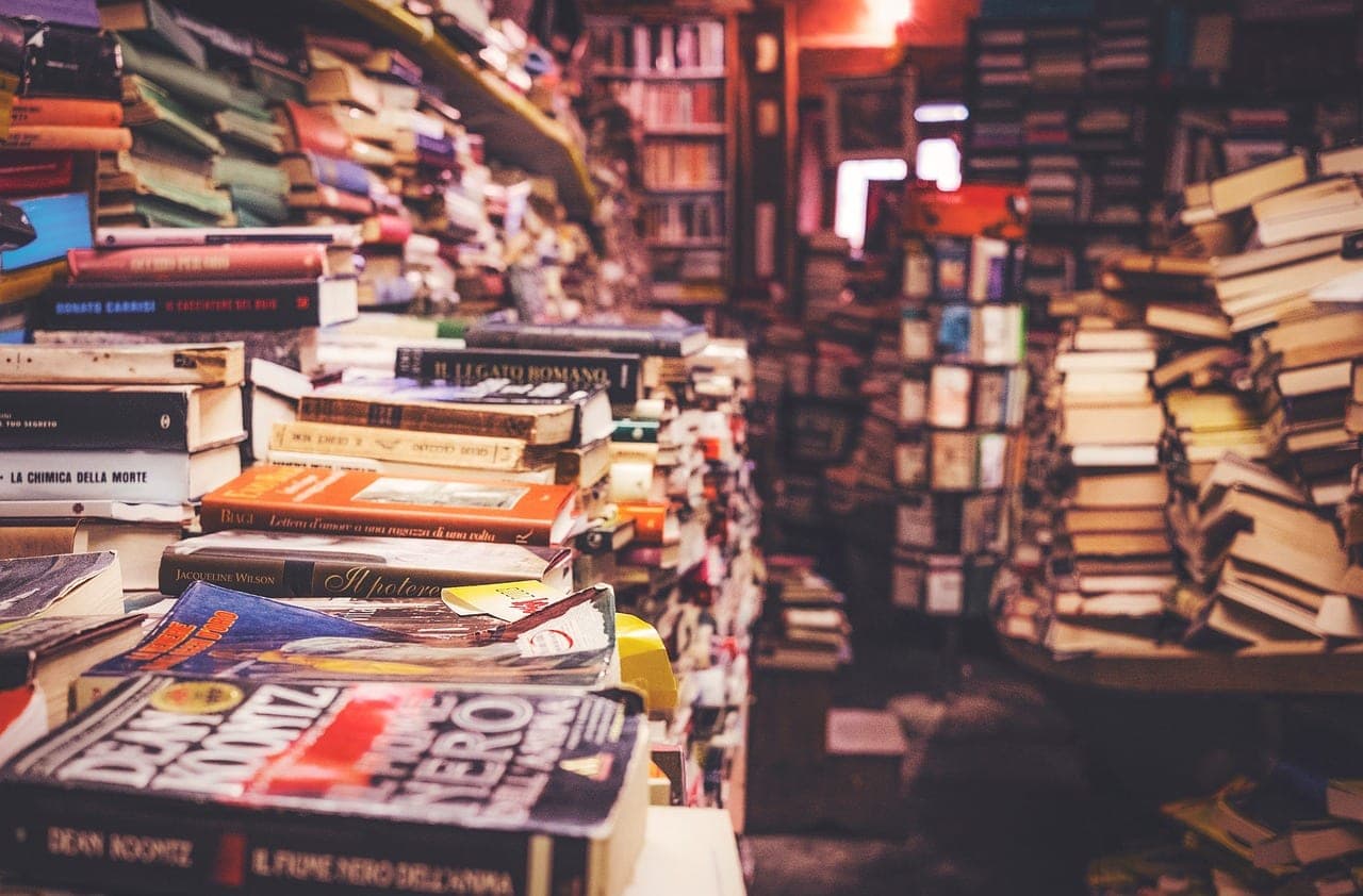 A crowded bookshop, books piled on the tables and up to the shelves at the back.