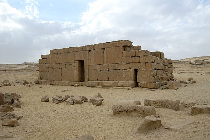 The bare stone temple standing alone at the desert's edge, its blocks still in place.