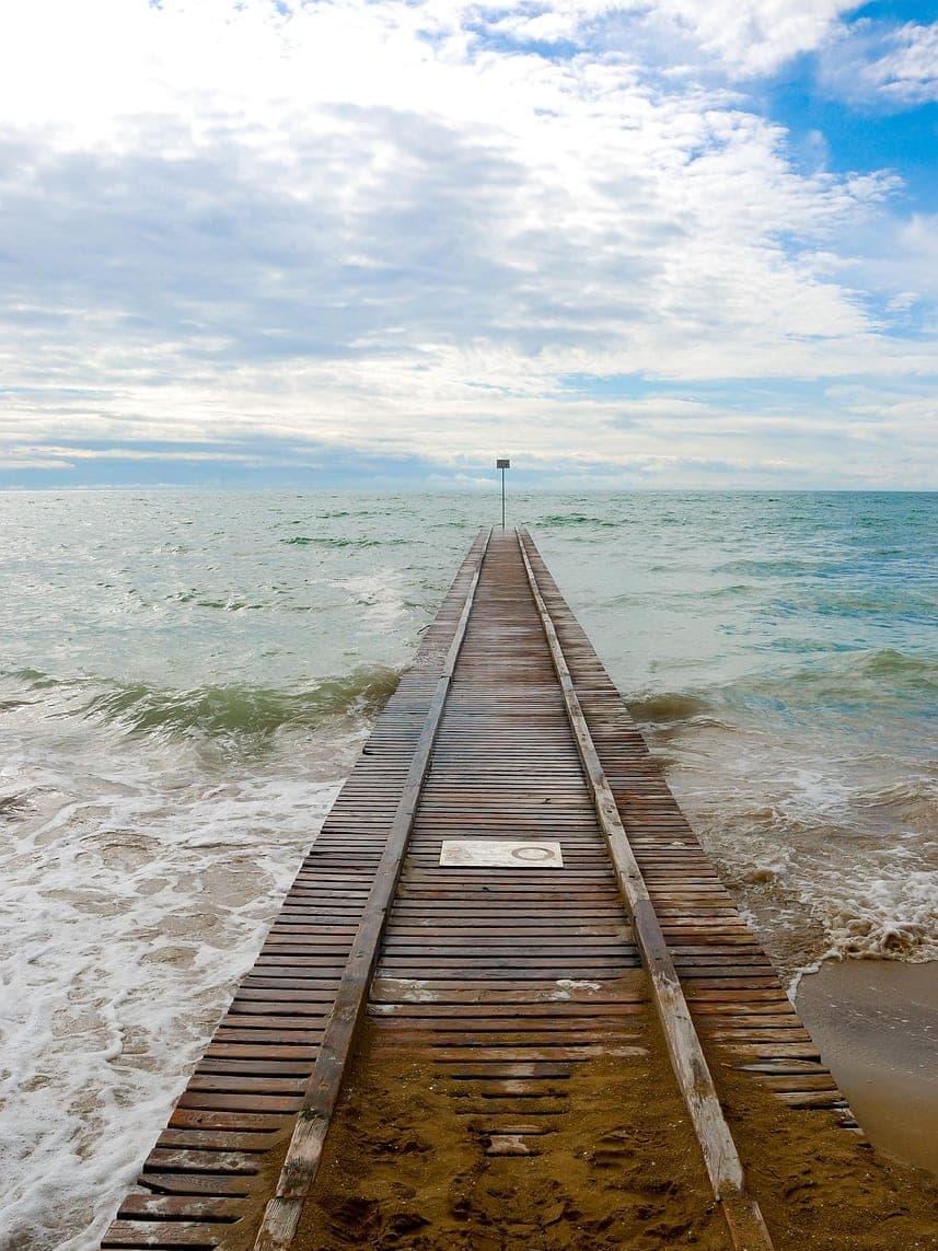 A wooden jetty running from the sand out into the sea.