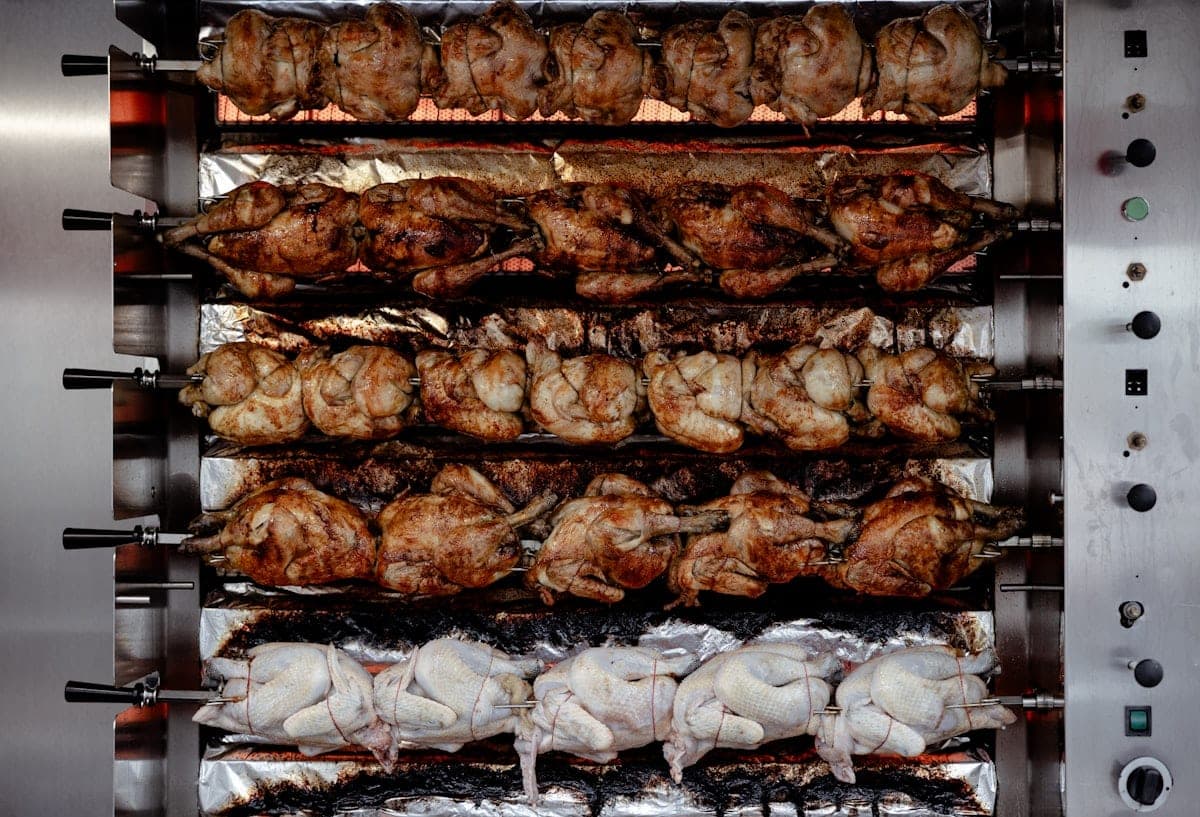 Chickens lined up on the spits of a rotisserie
