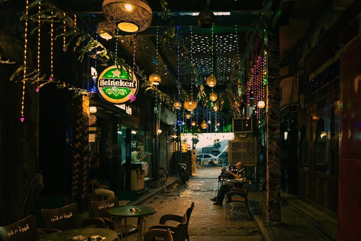 An alley lit by lanterns, tables set out for the evening