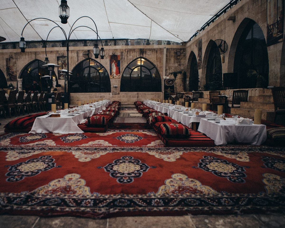 A vaulted hall, long tables and benches on the carpets