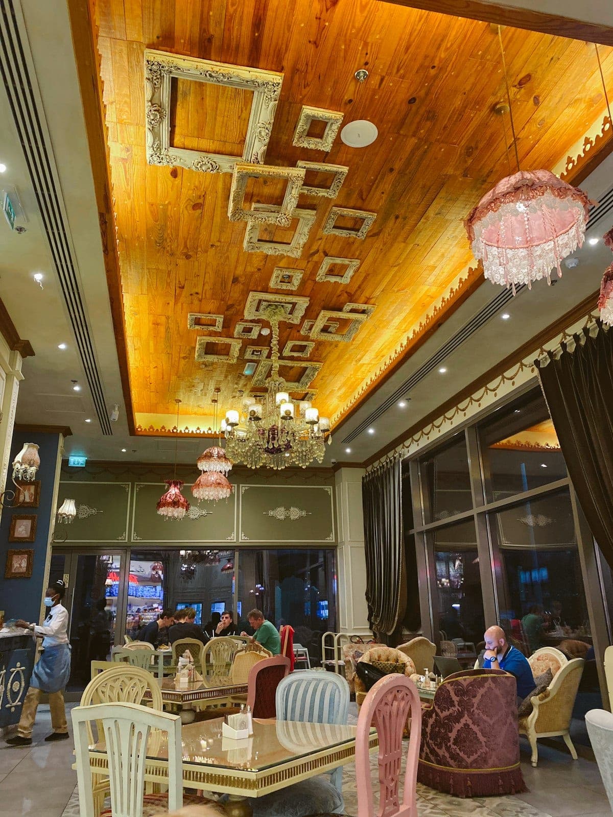A pastry salon with a carved ceiling and chandeliers