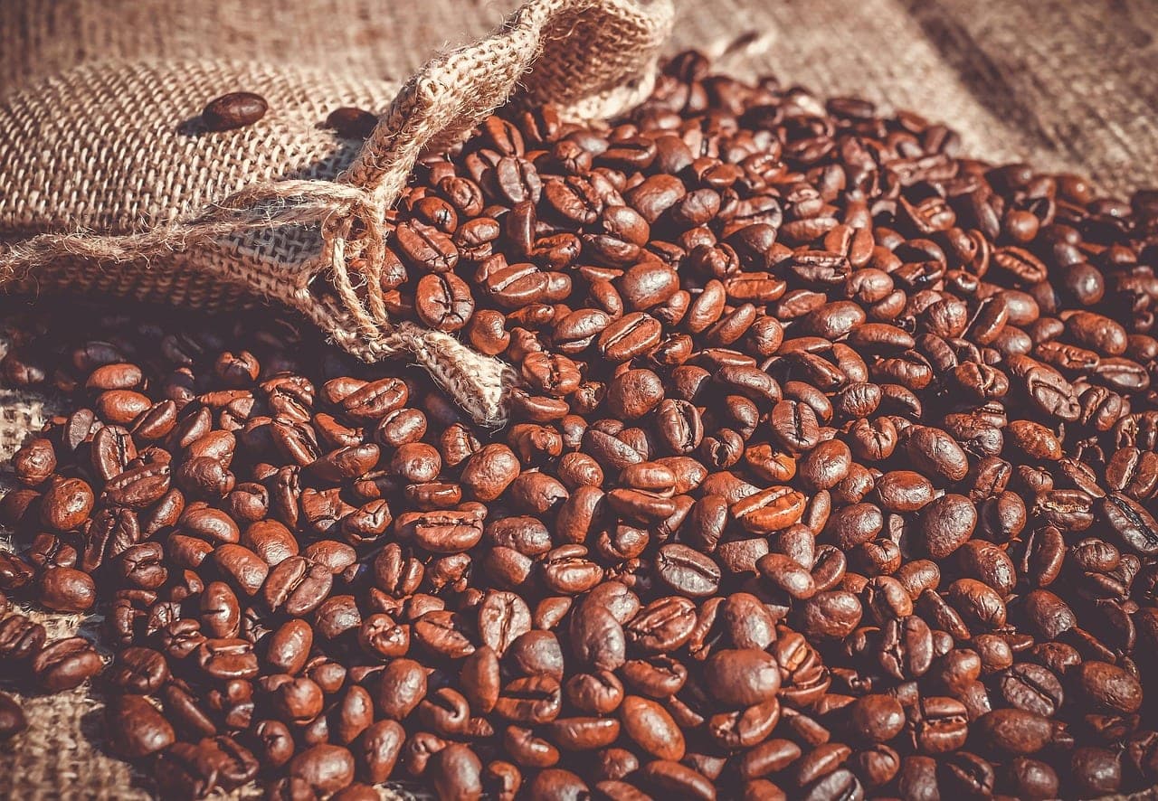Roasted coffee beans spilling out of a burlap sack.