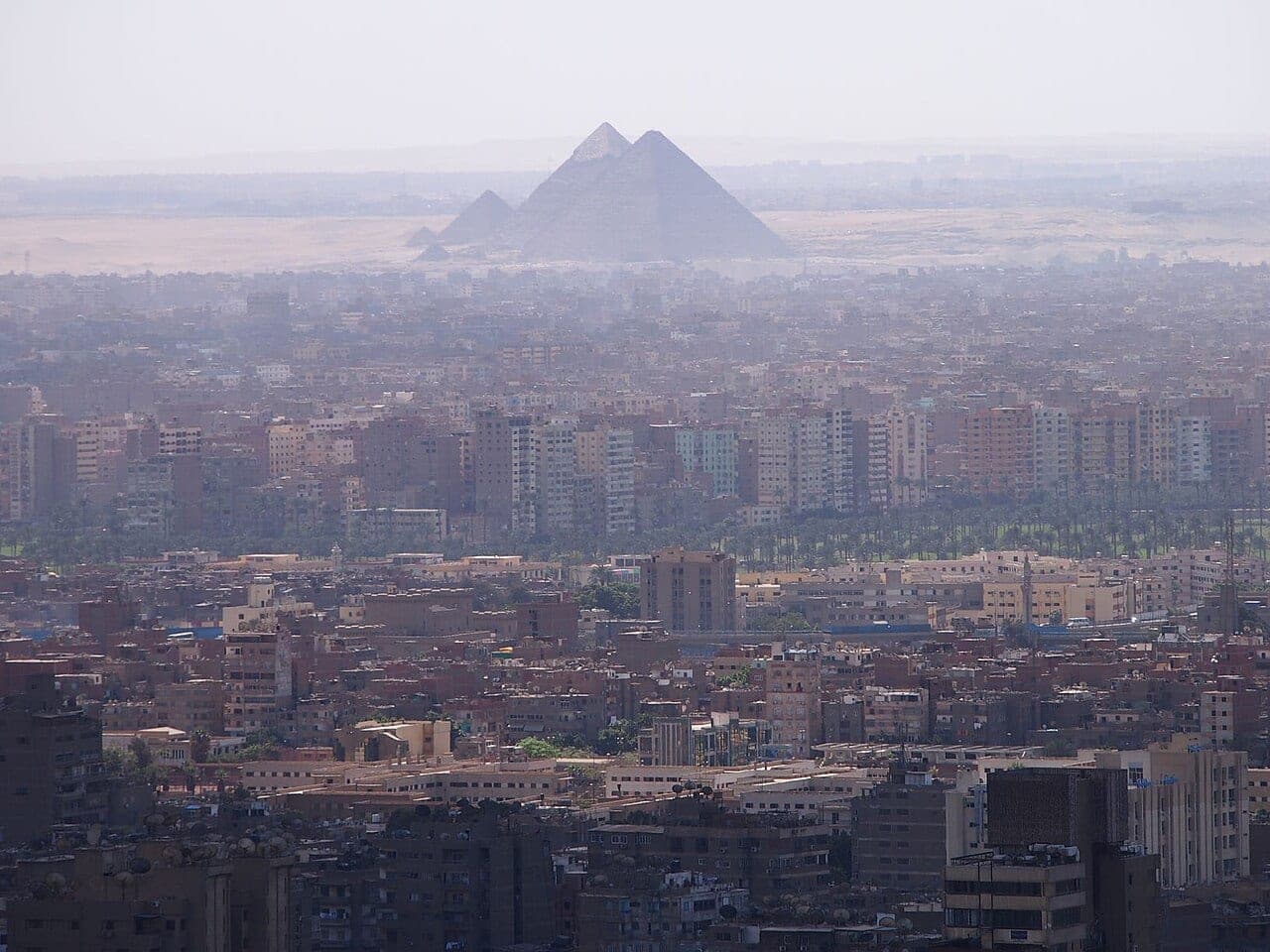 The Giza pyramids standing above the city rooftops in the heat haze.