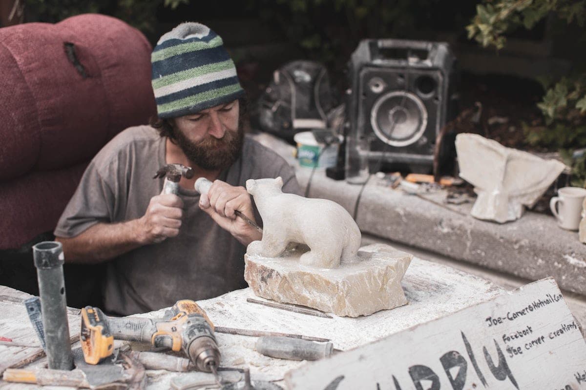 A stone carver at the chisel, on a pale block
