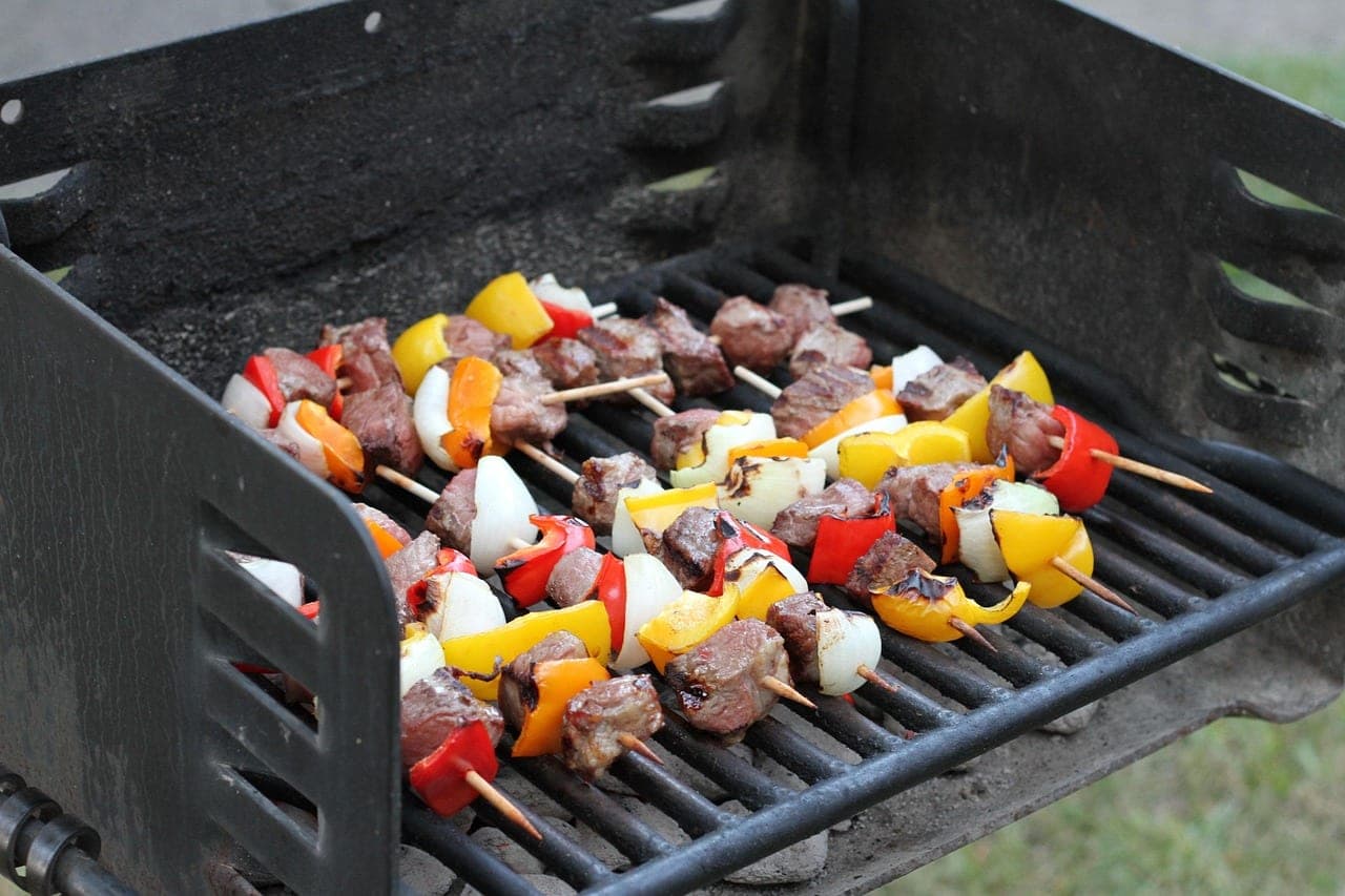 Meat, pepper and onion skewers on a charcoal grill.