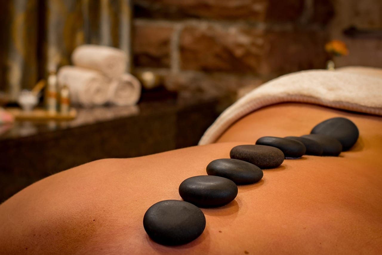 Hot stones lined up along a back, rolled towels in the background.