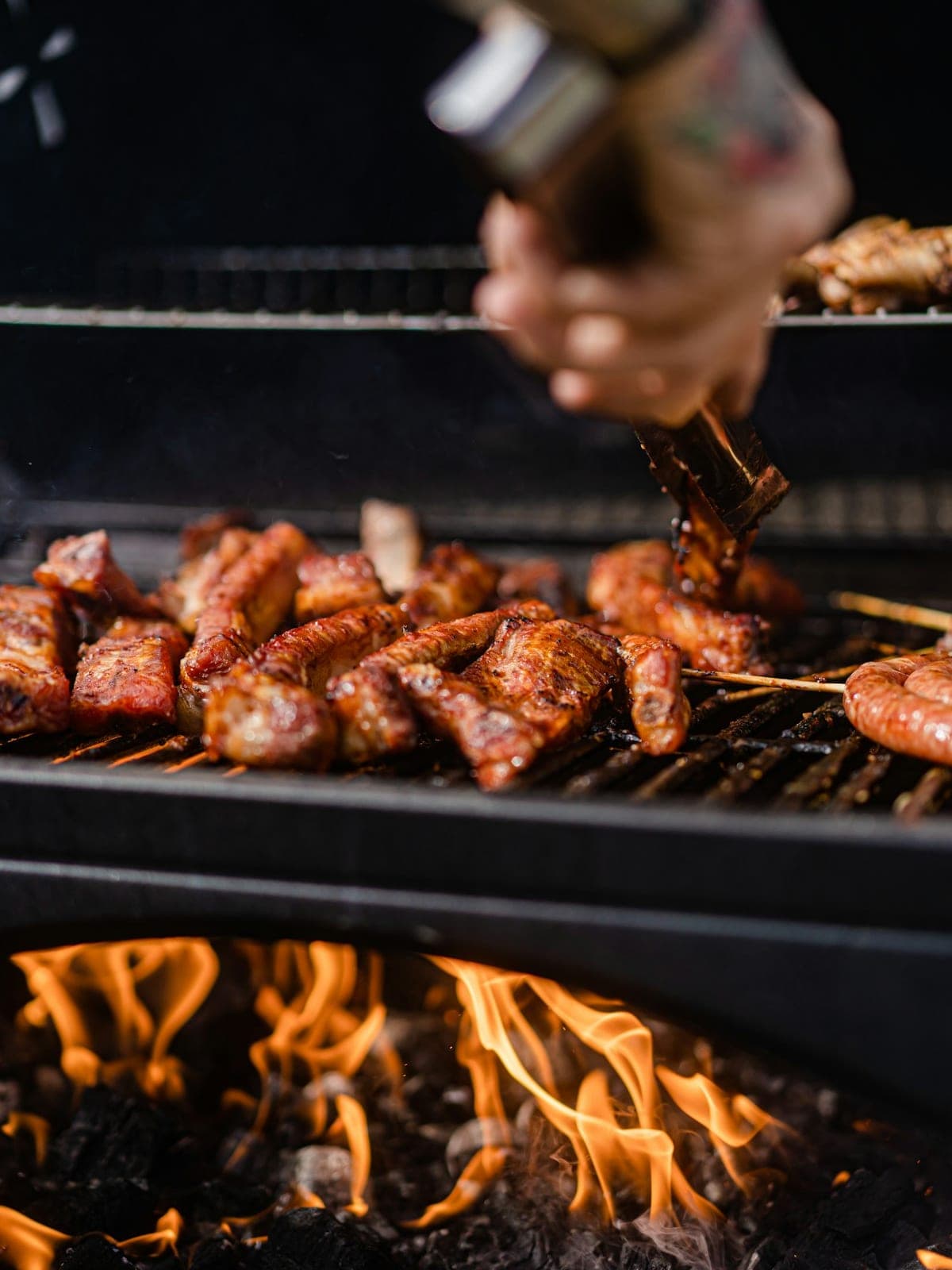 Meat turned with tongs, above the flames