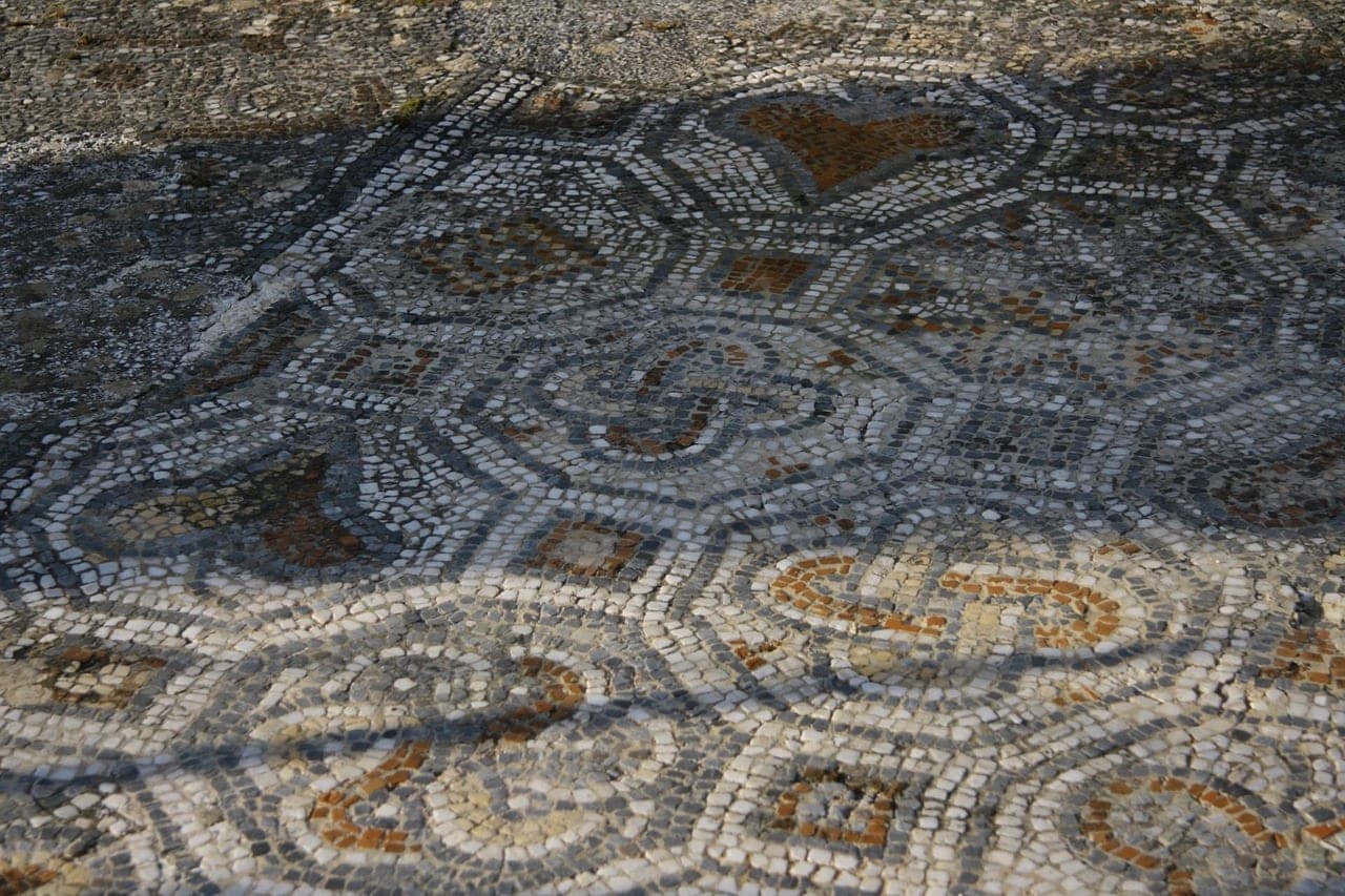 An ancient mosaic floor with geometric patterns, worn by time.