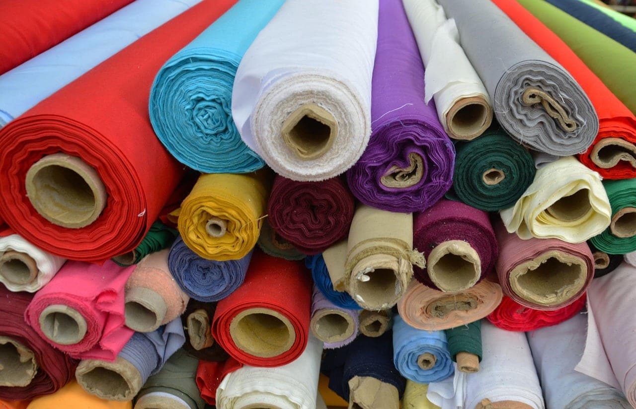 Rolls of fabric in every colour, stacked one on top of another.