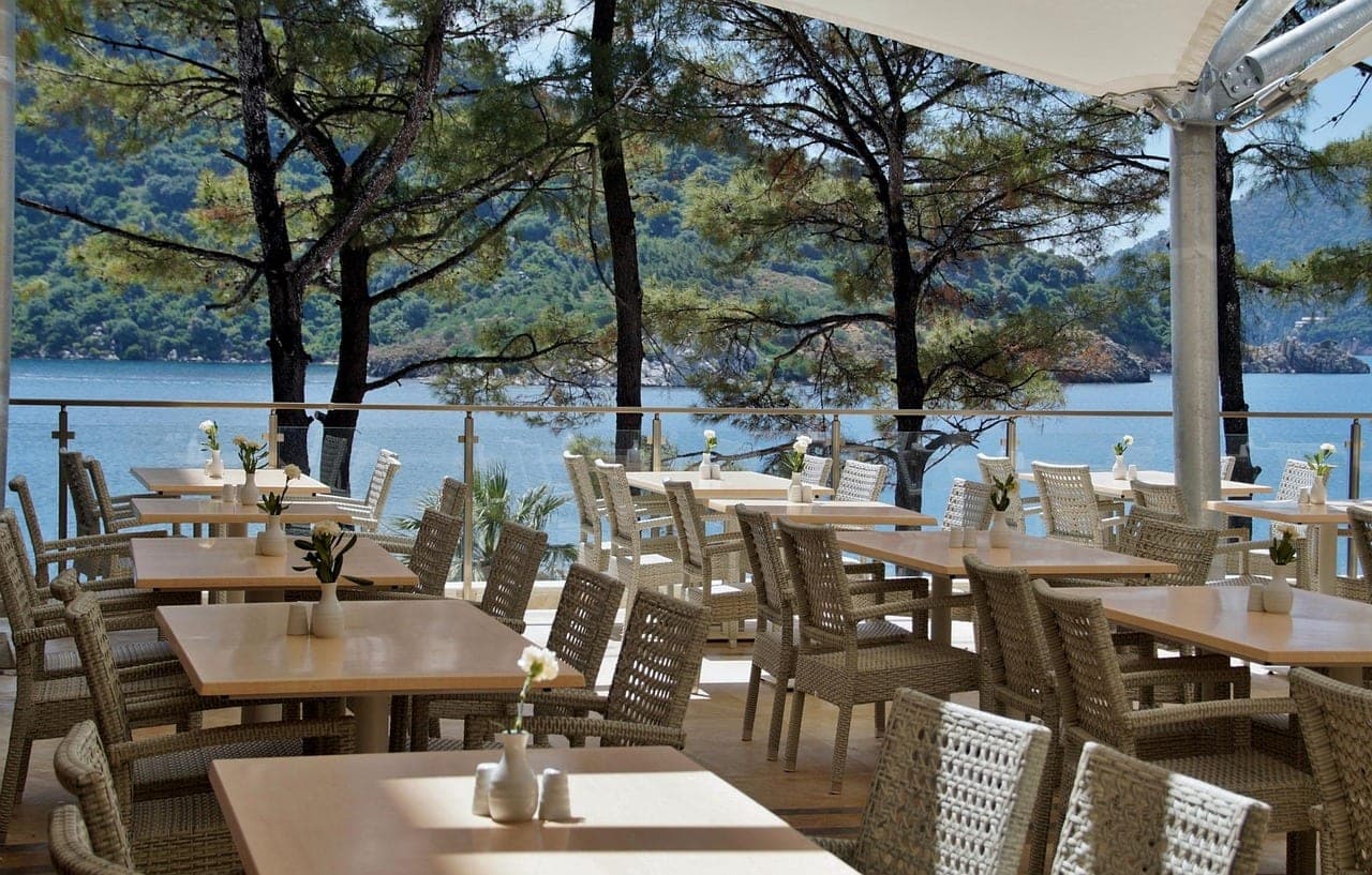 A restaurant terrace of laid tables, facing the sea.