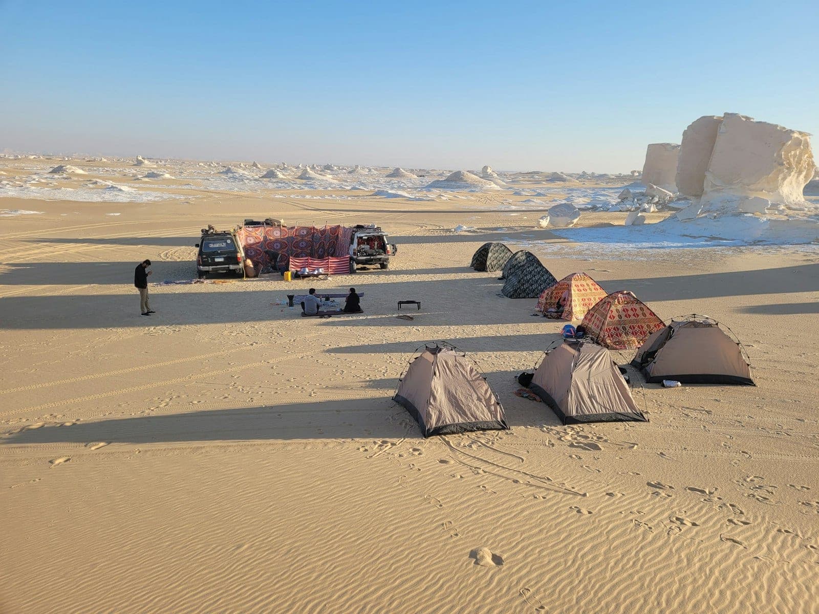Camp goes up at golden hour, among the white blocks.