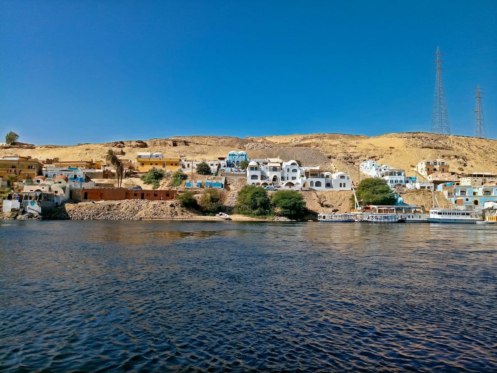The village from the Nile: houses climbing the slope, boats waiting.