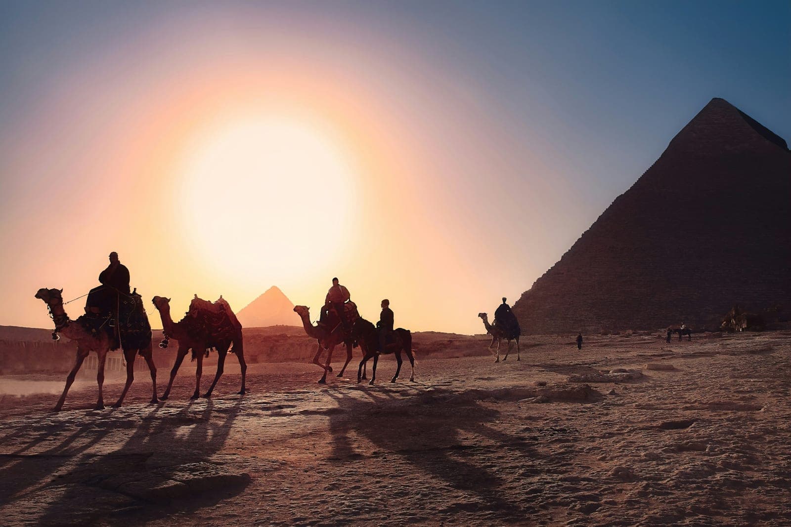 Camel riders at sunset near the Giza pyramids.